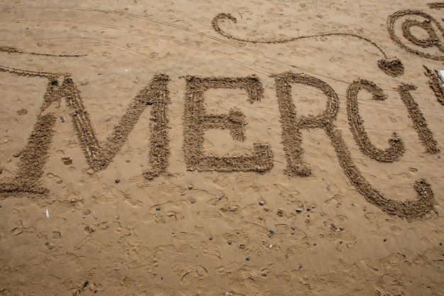 Merci signe français signifie Merci texte écrit sur la plage de sable