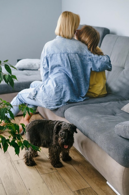 Mère avec une adolescente étreinte sur le canapé avec le chien