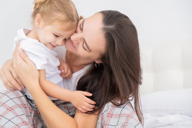 mère adulte embrassant sa petite fille à la maison, s'amusant.