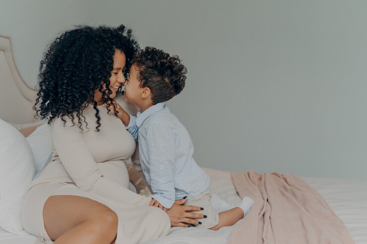 Photo mère afro-américaine et petit fils assis sur le lit et se touchant avec le nez