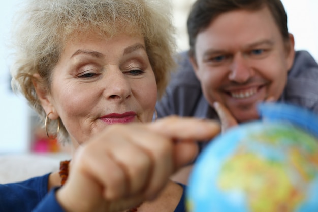 Une mère âgée montre un globe terrestre pour un fils adulte