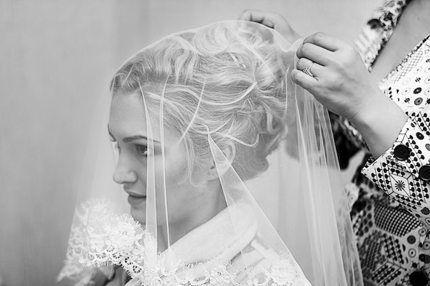 Mère aidant la jeune belle mariée à s'habiller pour la cérémonie de mariage. Photographie noir et blanc