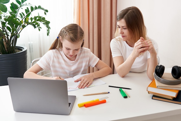 Mère aidant sa fille à faire ses devoirs. Le concept de l'enseignement à domicile en quarantaine. Difficultés de l'apprentissage à distance