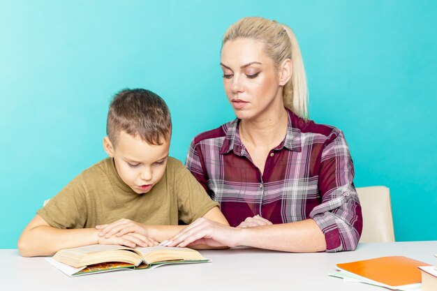 Mère aidant son fils à faire ses devoirs sur fond rose isolé. L'éducation à distance.