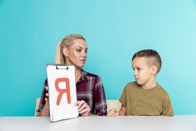 Mère aidant son fils à faire ses devoirs sur fond rose isolé. L'éducation à distance.