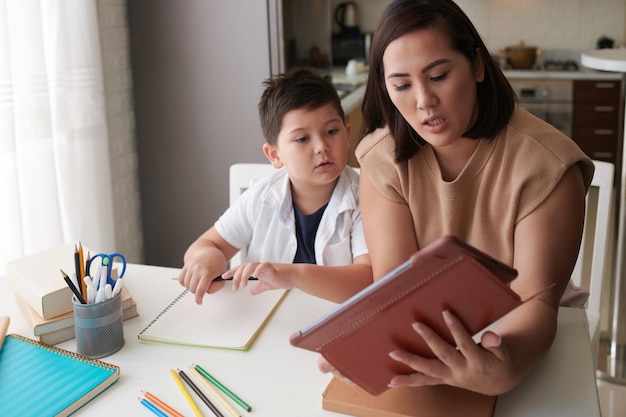 Mère aidant son fils à télécharger du matériel d'étude via une application sur une tablette