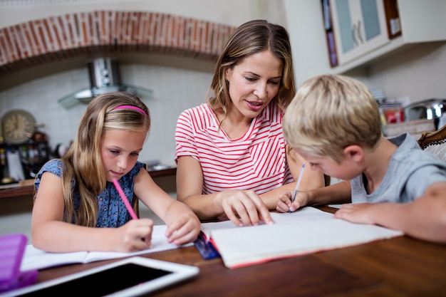 Une mère aide ses enfants à faire leurs devoirs