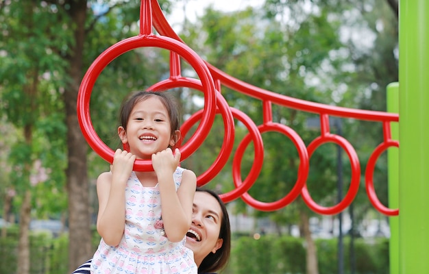 Mère aider sa fille à jouer sur le ring de gymnastique sur l&#39;aire de jeux en plein air.