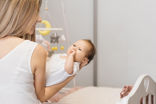 Une mère aimante porte son bébé nouveau-né à la maison portrait d'une mère heureuse tenant un bébé endormi dans ses bras Mère étreint sa petite fille de 4 mois