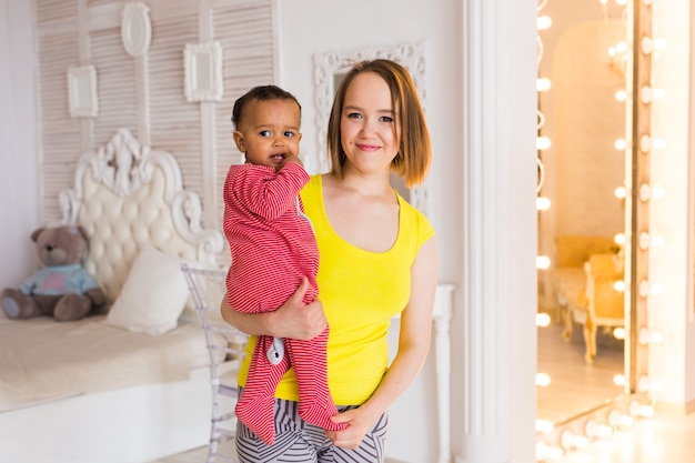 Mère aimante tenant bébé garçon métisse à la maison