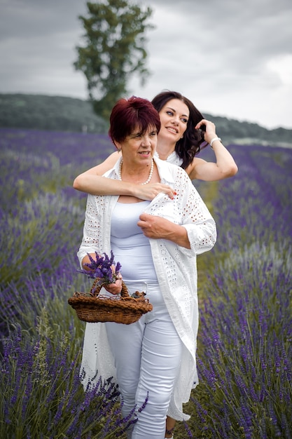 Mère aînée avec sa fille adulte marchant sur le champ de lavande