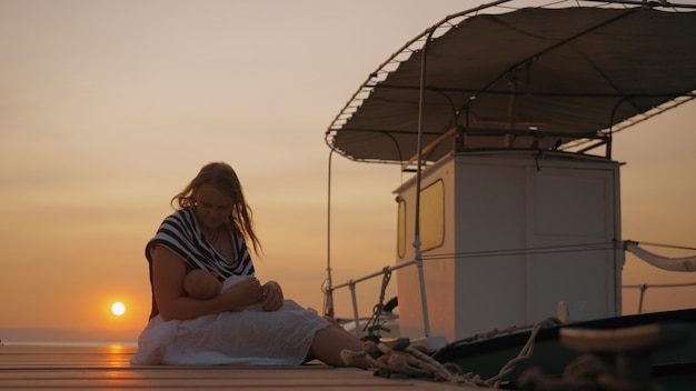 Mère allaitant bébé à quai au coucher du soleil