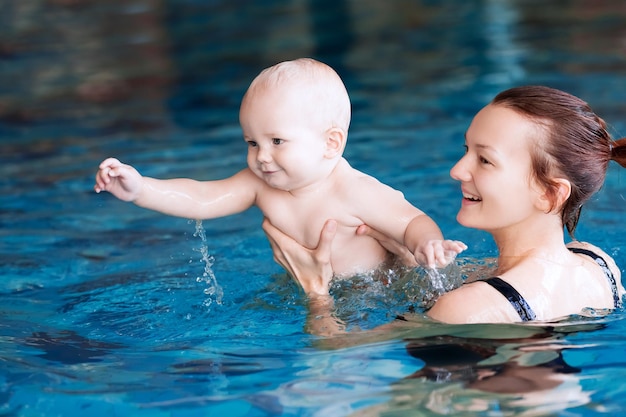 Mère apprenant à nager à bébé Portrait d'un enfant de 11 mois dans la salle de classe dans une piscine