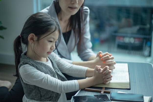 Mère apprenant à sa fille à prier et à lire la bible