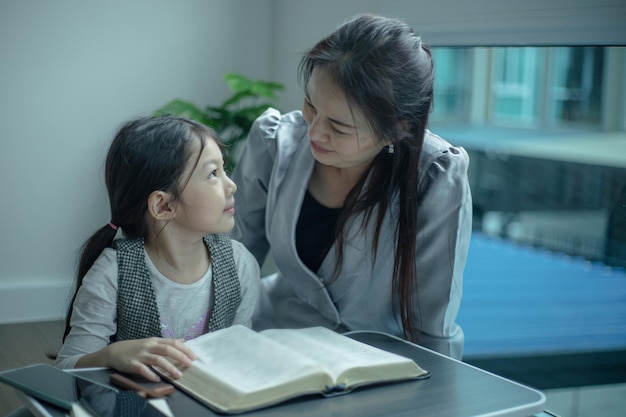 Mère apprenant à sa fille à prier et à lire la bible