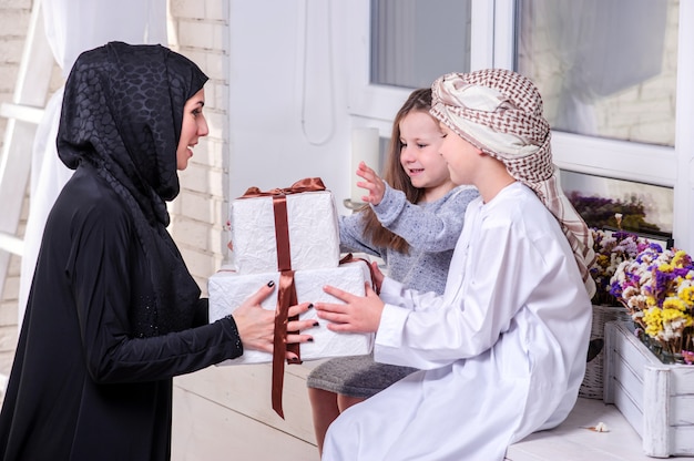 Mère arabe et enfants posant avec cadeau.