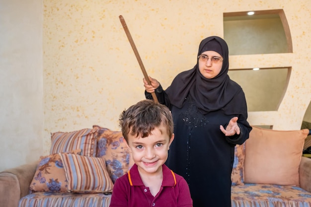 Mère arabe tellement en colère contre ses enfants et tenant un bâton pour le frapper