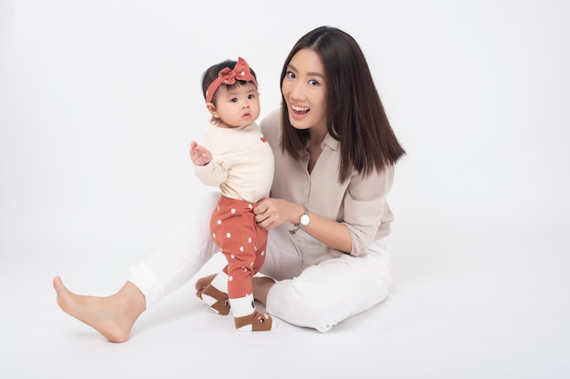 Mère asiatique et adorable petite fille sont heureux sur le mur blanc