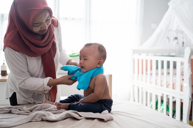 Mère asiatique changeant ses vêtements de bébé