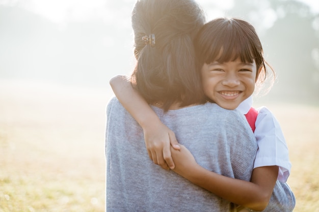 Une mère asiatique embrasse et embrasse sa fille qui va à l'école