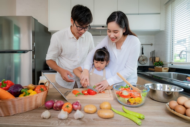 Mère asiatique enseignant à sa fille salade de légumes déchiquetés.