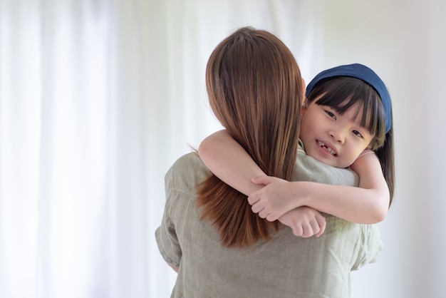 Une mère asiatique fait l'amour avec un câlin chaleureux sa jolie fille à la maison