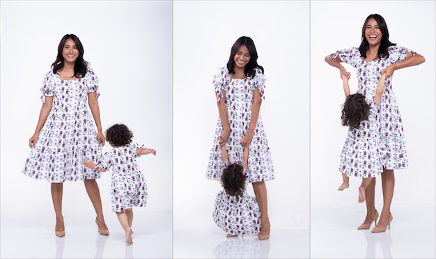 La mère asiatique et la fille caucasienne se tiennent debout et portent ensemble la même robe chemisier à fleurs violettes. La petite fille tient la main de maman et sourit avec amour. Fond blanc isolé