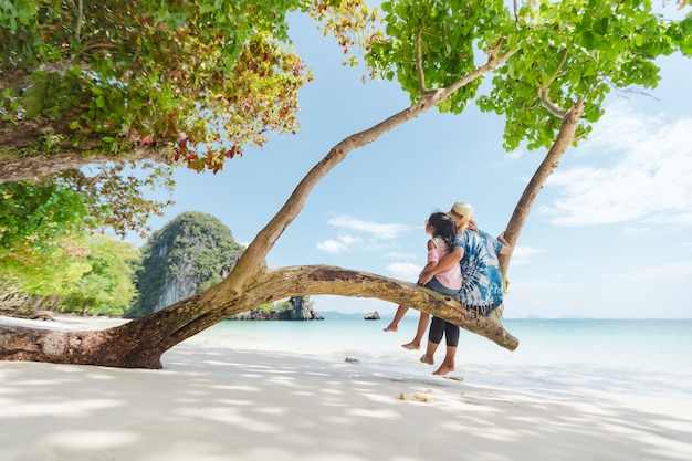 Mère asiatique et fille enfant assise sur l'arbre et profiter de la belle nature de la mer ensemble pendant leurs vacances.