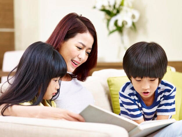 une mère asiatique lisant un livre avec deux enfants