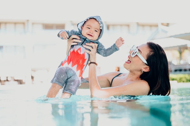 Mère asiatique et petit-fils appréciant la baignade dans une piscine en vacances d'été.