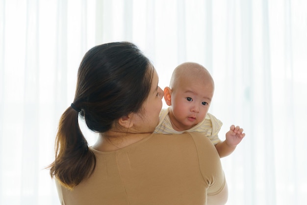 Une mère asiatique tient son fils nouveau-né dans la chambre à la maison, ce qui représente l'amour et le lien entre la mère et le fils
