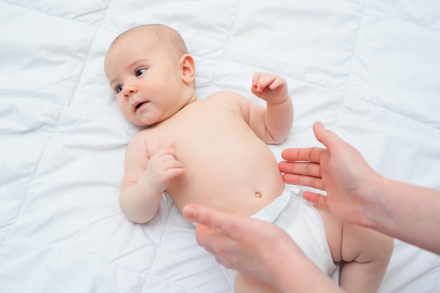 Une mère attentionnée donne à son bébé un massage du ventre et aide à se débarrasser des coliques.