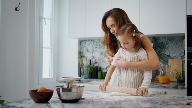 Mère attentionnée rouler les manches à sa fille au gros plan de la cuisine