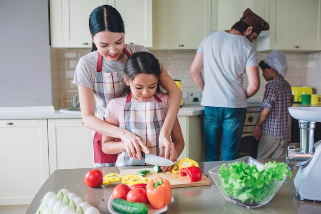 Une mère attentive aide son enfant à couper les légumes.