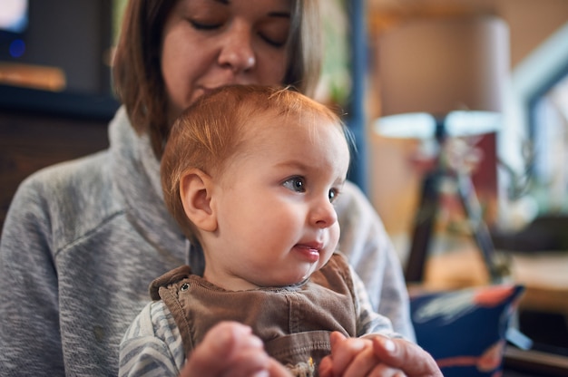 Mère avec un bébé de 1 an assis sur un canapé à la maison