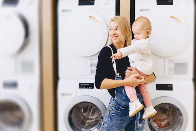 Mère avec bébé sur le fond des machines à laver