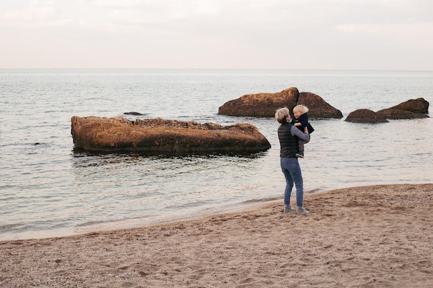 Mère et bébé garçon près du bord de la mer en automne