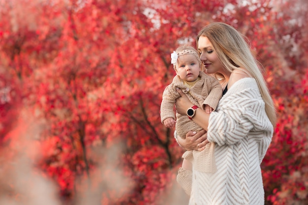 Mère et bébé. Image émotionnelle sensuelle. Parc d'automne. beaux arbres rouges.