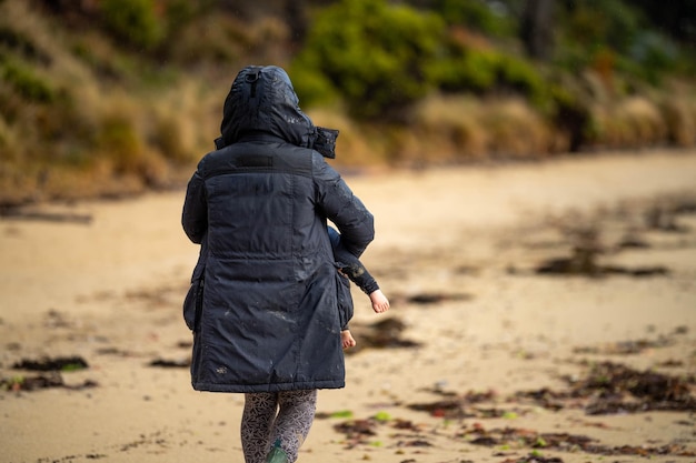 mère et bébé jouant sur la plage bambin en salopette marchant et jouant avec du sable et des chiens au bord de la mer