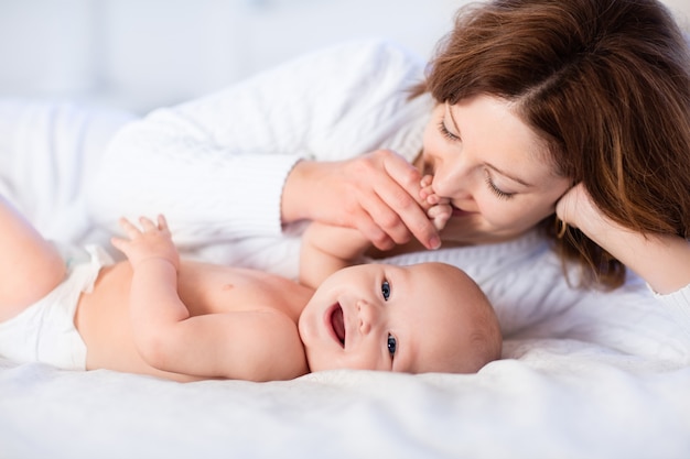 Photo mère et bébé sur un lit blanc