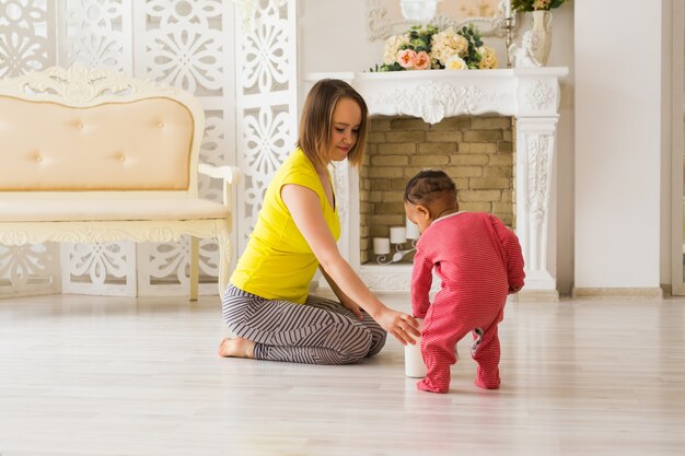 Mère et bébé de race mixte jouant à la maison.