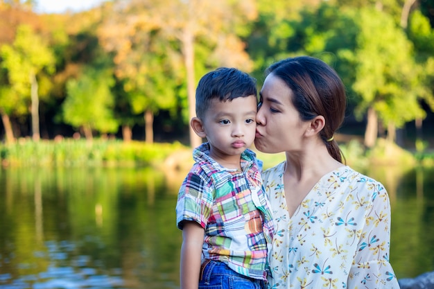 Photo mère et bébé sont heureux, souriants, profitant de l'air chaud et pur dans un beau jardin.