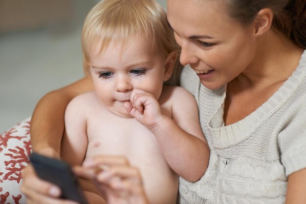 Mère et bébé ou sourire avec Internet pour la diffusion de vidéos sur les réseaux sociaux ou des dessins animés pour le développement Famille femme et tout-petit ou enfant avec smartphone pour la recherche de défilement et le divertissement