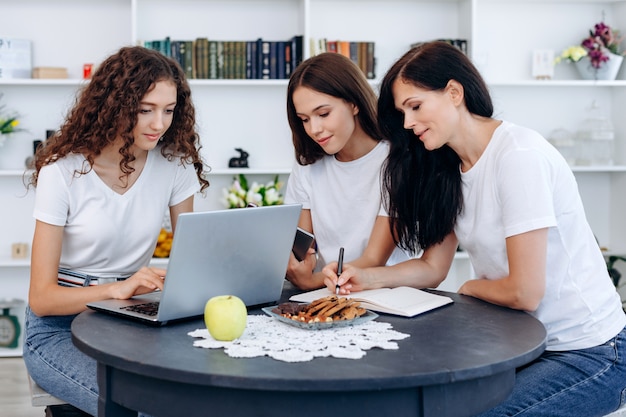 Mère avec de belles filles travaillant à table à la maison