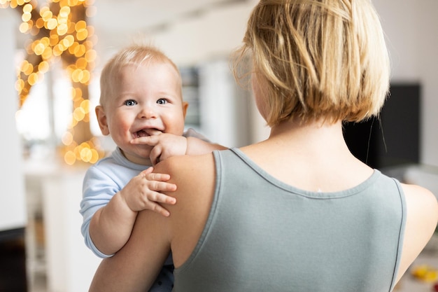 La mère blonde tenant son adorable bébé joyeux bébé garçon bébé mignon regardant à l'intérieur