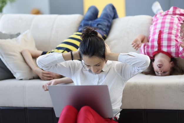 Une Mère Bouleversée Se Couvre Les Oreilles Avec Ses Mains Des Jeux Et De La Désobéissance Des Enfants Qui Se Tiennent à L'envers