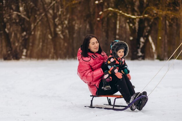 Mère brune et sa fille chevauchant un traîneau dans la forêt d'hiver Photo de haute qualité