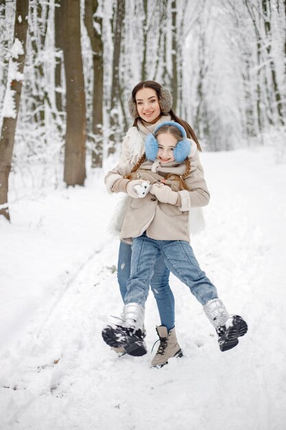 Mère brune et sa fille s'amusant dans la forêt d'hiver