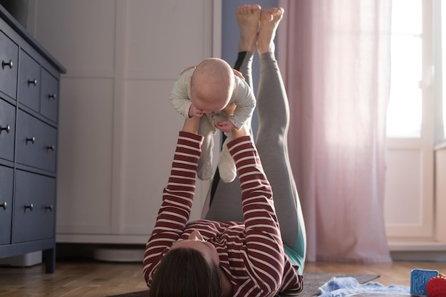 Une mère caucasienne avec un bébé fait du yoga à la maison pour être forte et en bonne santé