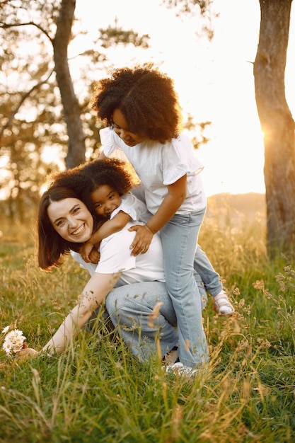 Mère caucasienne et deux de ses filles afro-américaines s'embrassant ensemble à l'extérieur